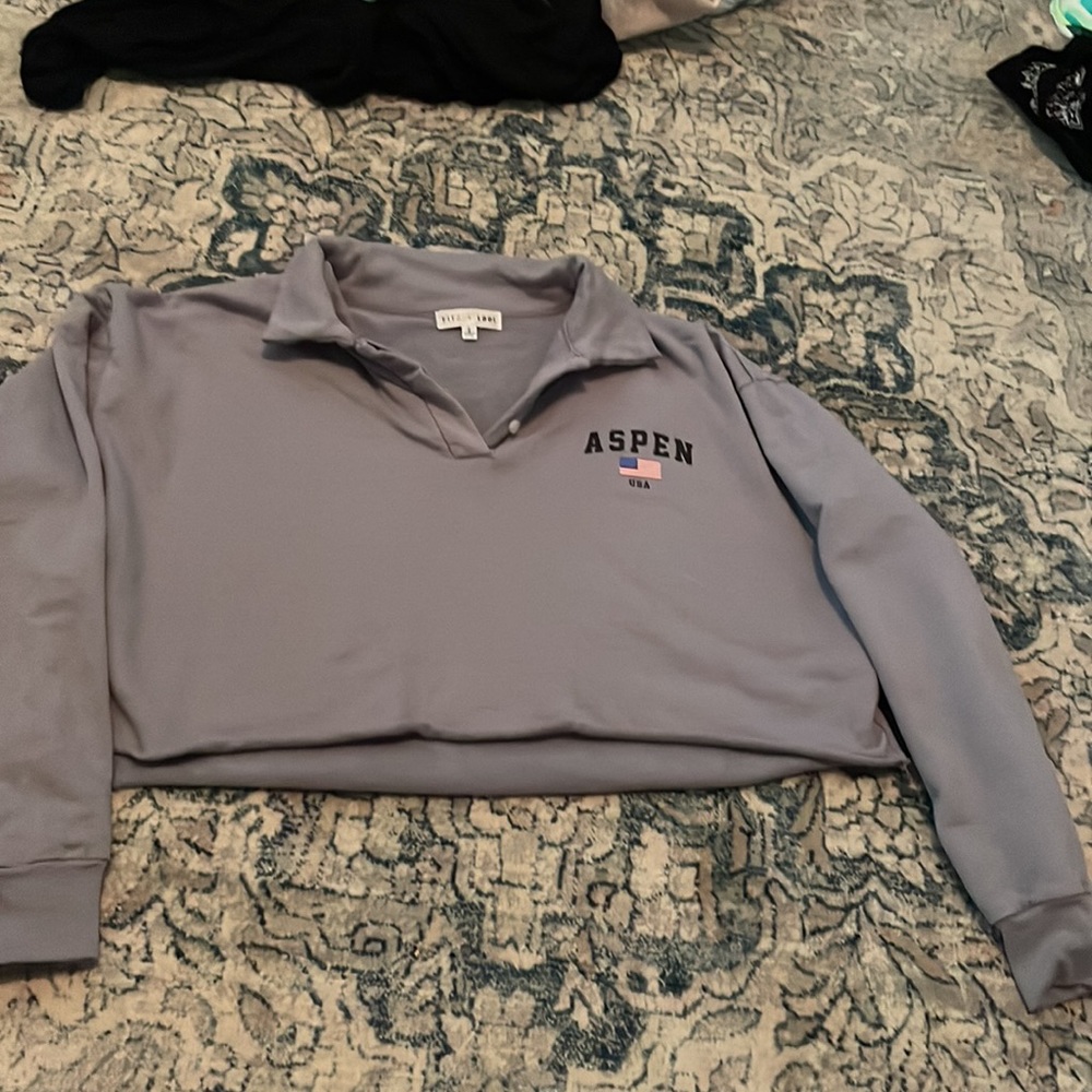 This is a crop top with long sleeves and a collar. It is a grey-blue color.